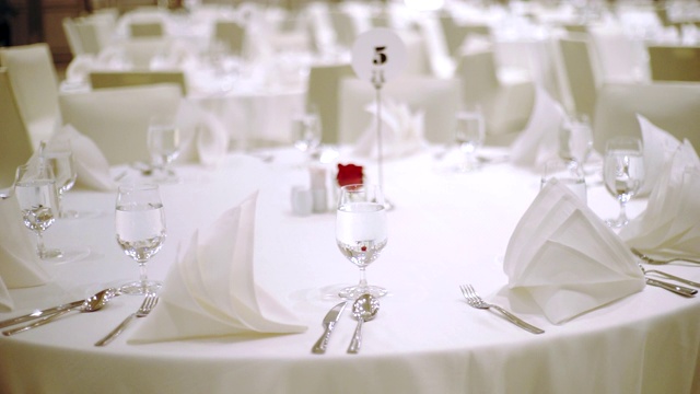 多莉女士右桌子的相机设置为婚礼招待会或活动派对与椅子和圆桌客人与陶器和覆盖在白色桌布室内。视频下载