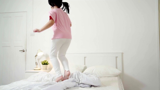 慢动作:年轻的亚洲快乐女孩有乐趣跳舞在床上在家里视频素材