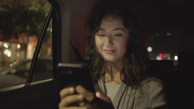 一名年轻女子晚上在汽车后座上工作视频素材