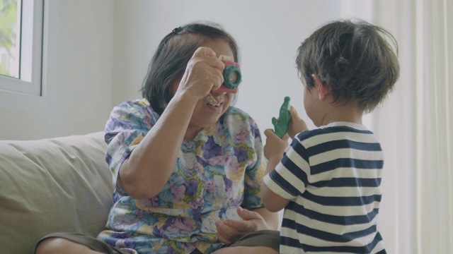 奶奶和孙子在家里玩玩具。视频下载