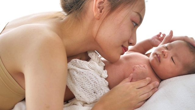 美丽年轻的亚洲母亲与她的新生儿躺在床上在家里视频素材