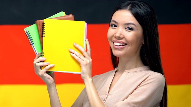 快乐的学生展示笔记本德国国旗的背景，在大学教学视频下载