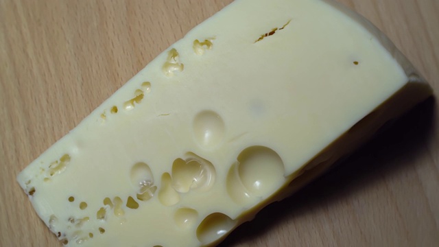 带有孔的奶酪在木制背景上旋转。视频下载
