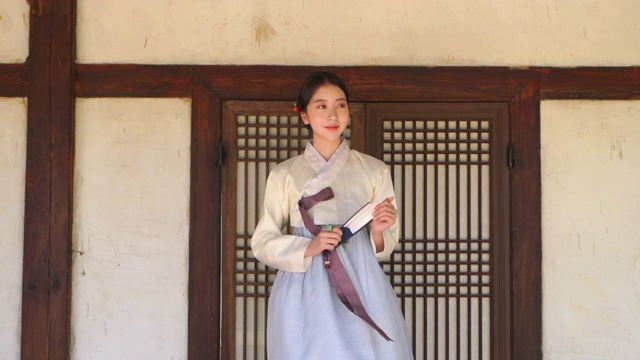 身着韩服(朝鲜王朝的传统服装)的女子打开折扇，给自己扇风视频下载