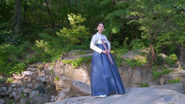 韩服(朝鲜王朝的传统服装)站在一块岩石上视频下载