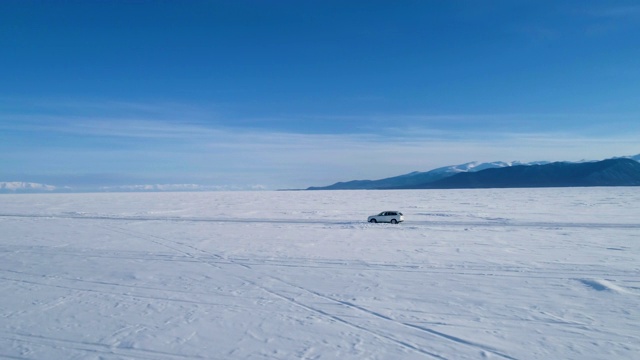 白色越野车行驶在空旷的贝加尔湖白雪覆盖的表面。视频素材