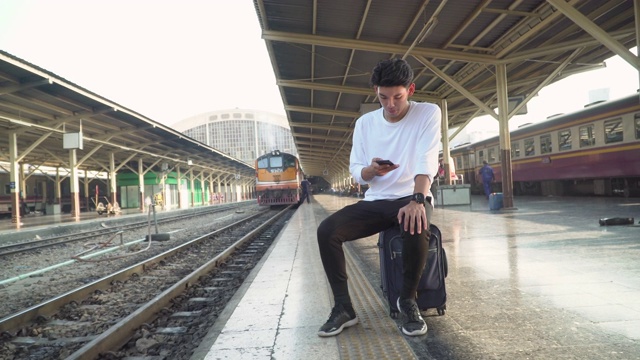 年轻男性游客在火车站使用手机视频素材