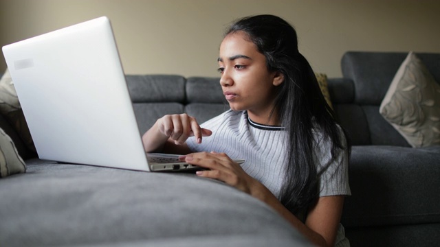 年轻女孩正在用笔记本电脑放松视频下载