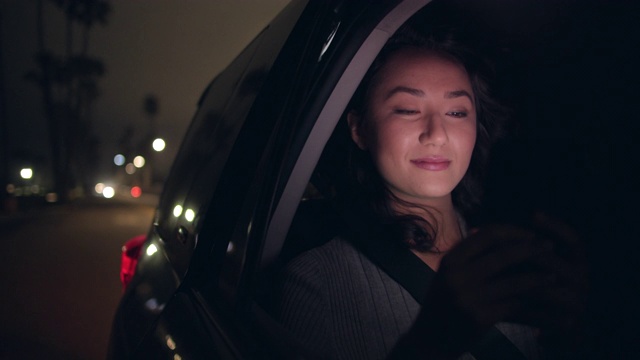 一名年轻女子晚上坐在一辆车里视频素材