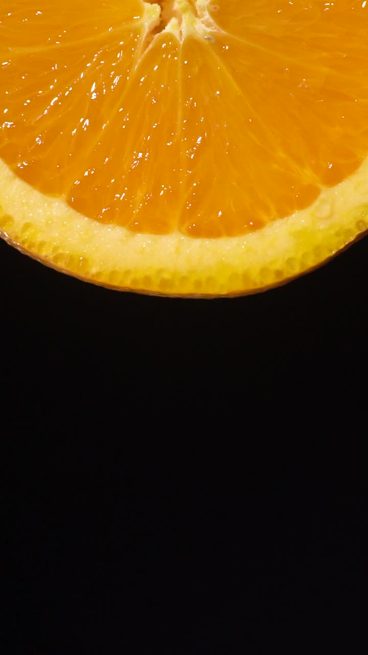 垂直和慢动作:许多雨滴从橙色切片在黑色视频素材