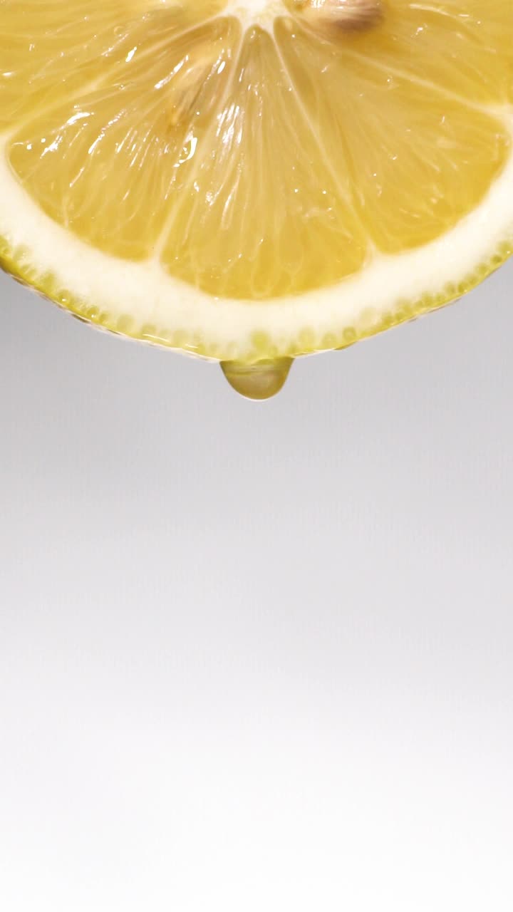垂直和慢动作:许多液体从柠檬片在白色视频素材