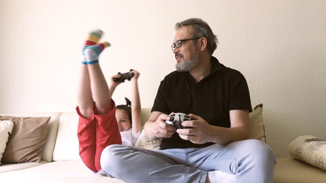 兴奋的儿子和父亲按控制台的按钮，同时玩电子游戏视频素材