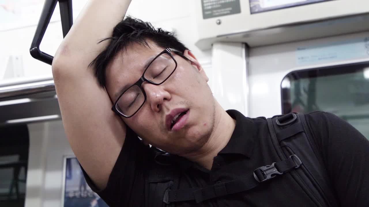 一个疲惫的人站在地铁上睡觉。视频素材