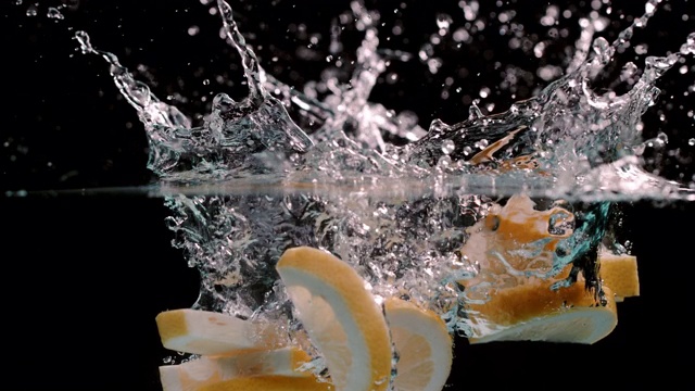 超级慢动作:切成一半的柠檬溅进水里视频素材
