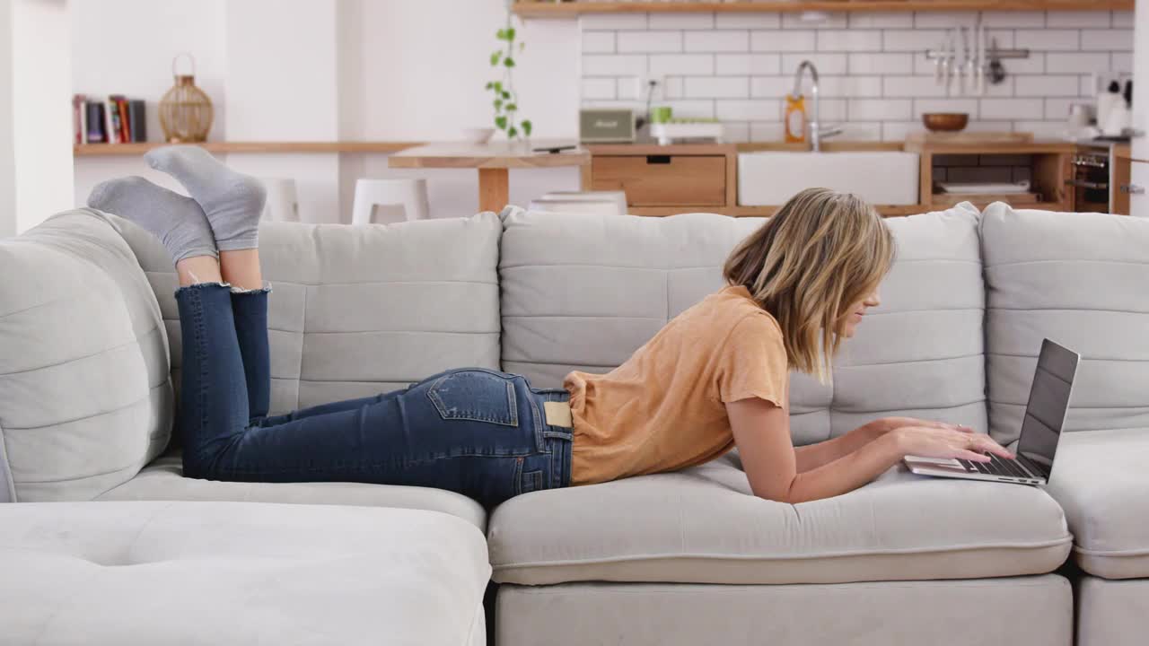 躺在沙发上放松的女人用笔记本电脑工作视频下载