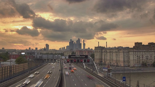 前景是宽阔的城市高速公路上密集的交通，背景是日落时的办公大楼视频素材