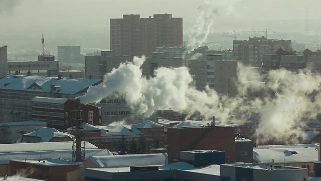 在冬天阳光明媚的日子里，工业管道产生的烟雾污染了城市的空气。环境污染:管道有烟。视频素材