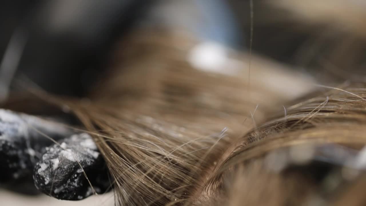 理发师在棕色头发上使用染发剂的特写视频下载