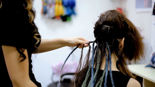 女孩发型师在沙龙里为客户编辫子视频下载