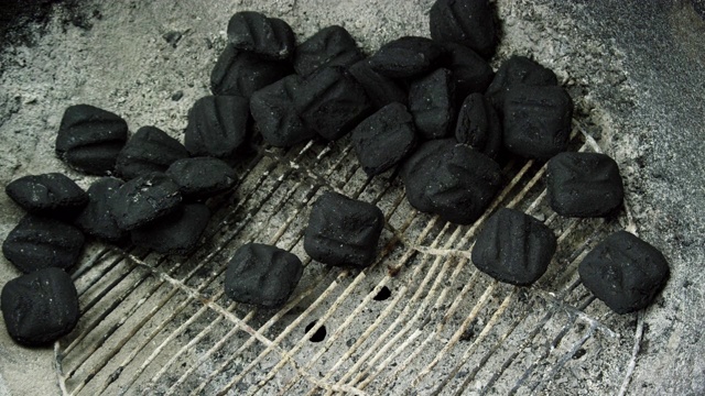 在准备烧烤时，木炭团落在户外烧烤架的金属格栅顶部视频素材