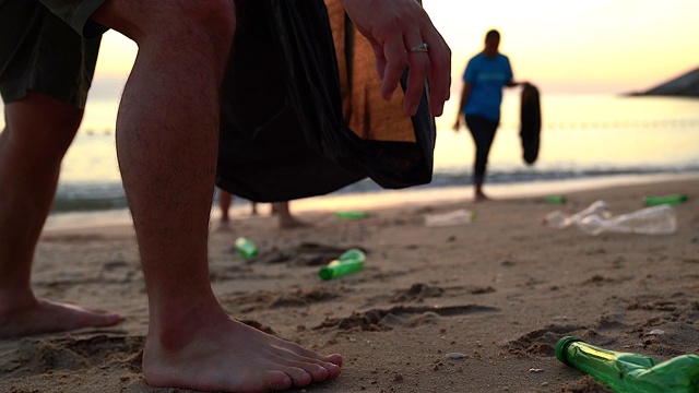 一群年轻的志愿者帮助保持自然清洁，并在沙滩上捡拾垃圾。视频素材
