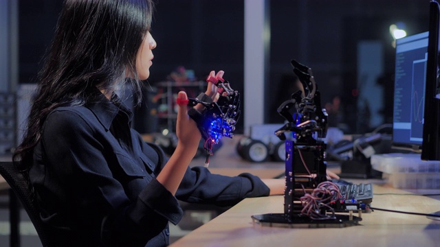 一个未来主义的假肢机器人手臂由一个十几岁的女孩开发工程师在一个研究实验室工作到深夜。手臂移动手指。教育、技术、团队合作、后期工作、科学人本理念。教育的主题。4.0行业视频下载