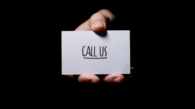 一只手在黑色背景上孤立地展示着一张卡片，上面写着“呼叫我们”。视频下载