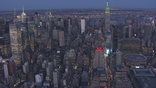 曼哈顿中城及周围的纽约市天际线的航拍。帝国大厦亮起了绿光。摩天大楼和高层写字楼或公寓。地标性建筑。纽约客酒店，宾夕法尼亚车站可见。视频下载