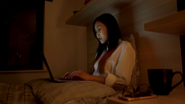 年轻的亚洲商务女性在家里用笔记本电脑工作到深夜视频下载