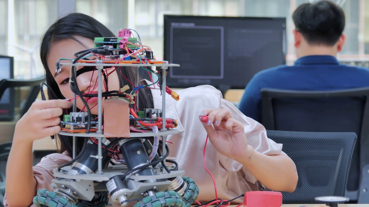 十几岁的女性正在为学校机器人俱乐部的项目设计一个功能齐全的可编程机器人。创意设计师在车间测试机器人原型。教育、科技、团队、科学、以人为本的理念。教育的主题视频下载