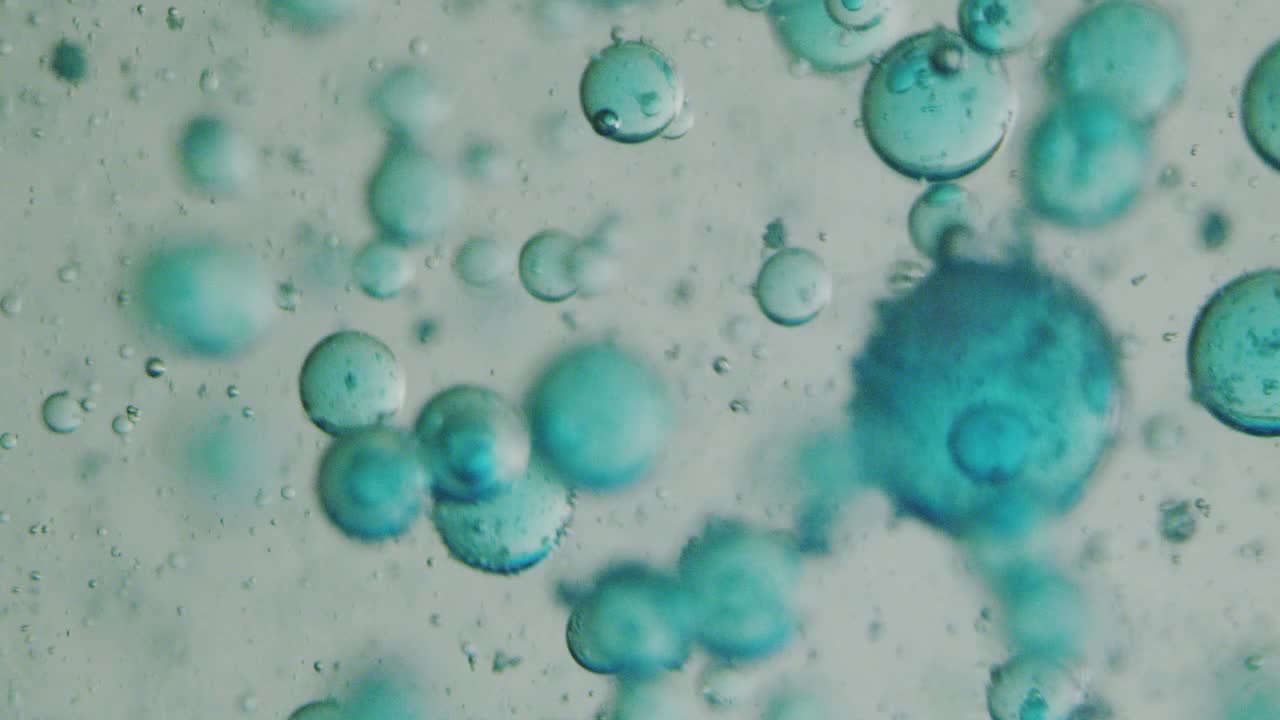 在科学实验室中，用显微镜对液体中蓝色微粒子分子的慢动作宏进行了分析，用于护肤美容化妆品的研究视频下载