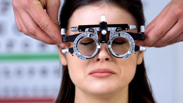 眼科医生将光镜放在受惊吓的女性病人的眼睛上，进行视力测试视频下载