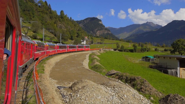 红色火车的一边从窗口，因为它移动过去农田和山景-瑞士阿尔卑斯山，瑞士视频素材