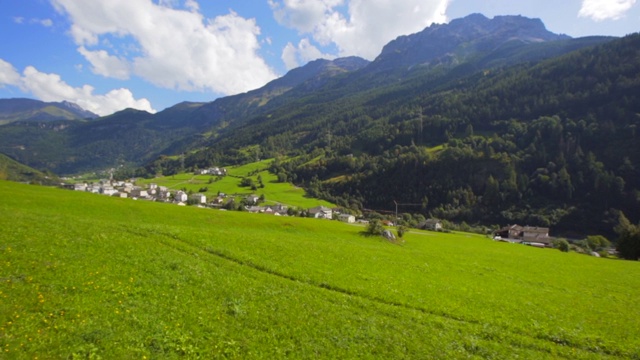 从移动的火车-瑞士阿尔卑斯山，瑞士的树覆盖的山的基地的房子排视频素材