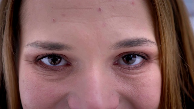 特写的年轻漂亮的白人女性的脸与棕色眼睛直视相机微笑的面部表情视频素材