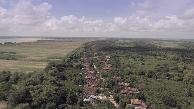 航拍滑块拍摄的主要街道对面的绿色村庄与多云的天空视频素材