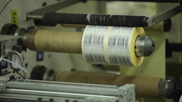 多标签印刷辊用于工业工厂的高速贴标机，用于生产不干胶产品。灵活的包装。特写宏。视频下载