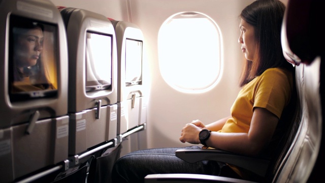 飞机内与女乘客在飞机客舱使用多媒体触摸屏，慢动作视频素材