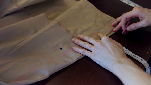 女裁缝在米色织物上标记一个图案视频素材