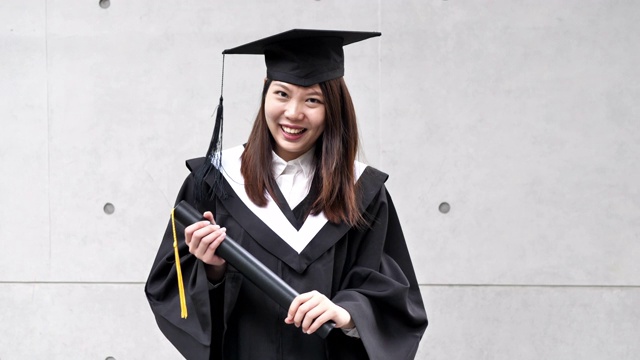 毕业在东亚-年轻女子微笑着长袍和帽子视频下载