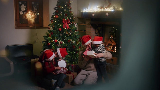 慢镜头中，一家人开心地庆祝圣诞假期，从下雪的窗口打开礼物。视频下载
