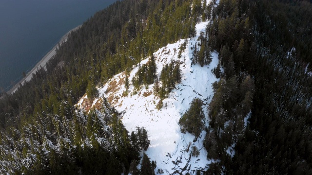 空中盘旋:白雪皑皑的山脉和湖边的森林，上面有白云——斯诺夸尔米，华盛顿视频下载