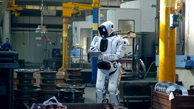 一个仿生机器人正在工厂里操作平板电脑视频素材