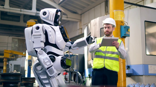 一名男性工程师正在控制一个机器人的运动视频素材
