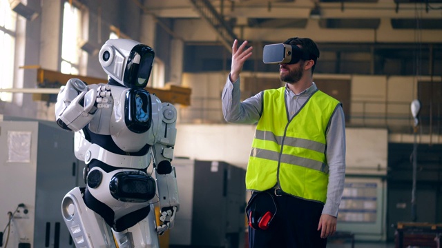 戴着虚拟现实眼镜的技术员和一个重复他动作的机器人视频素材