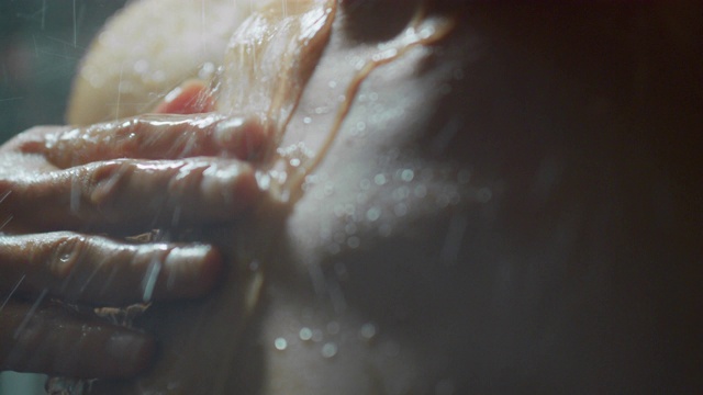 一个美丽的女人在淋浴洗自己在慢动作的电影镜头。视频素材