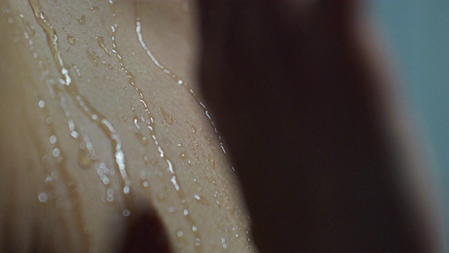 一个美丽的女人在淋浴洗自己在慢动作的电影镜头。视频素材