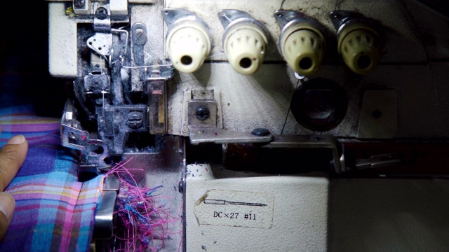 特写:女裁缝在包缝机上给布料缝边做衣服。视频下载