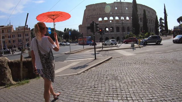 在欧洲的意大利罗马，一名妇女打着遮阳伞走过圆形竞技场。——延时视频素材