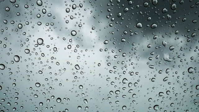 特写雨滴落在汽车前面的玻璃上，水滴落在玻璃上。视频素材